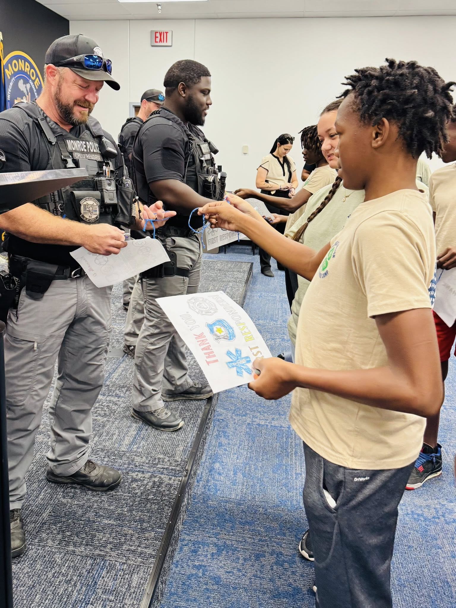 A kid handing a police officer a paper.